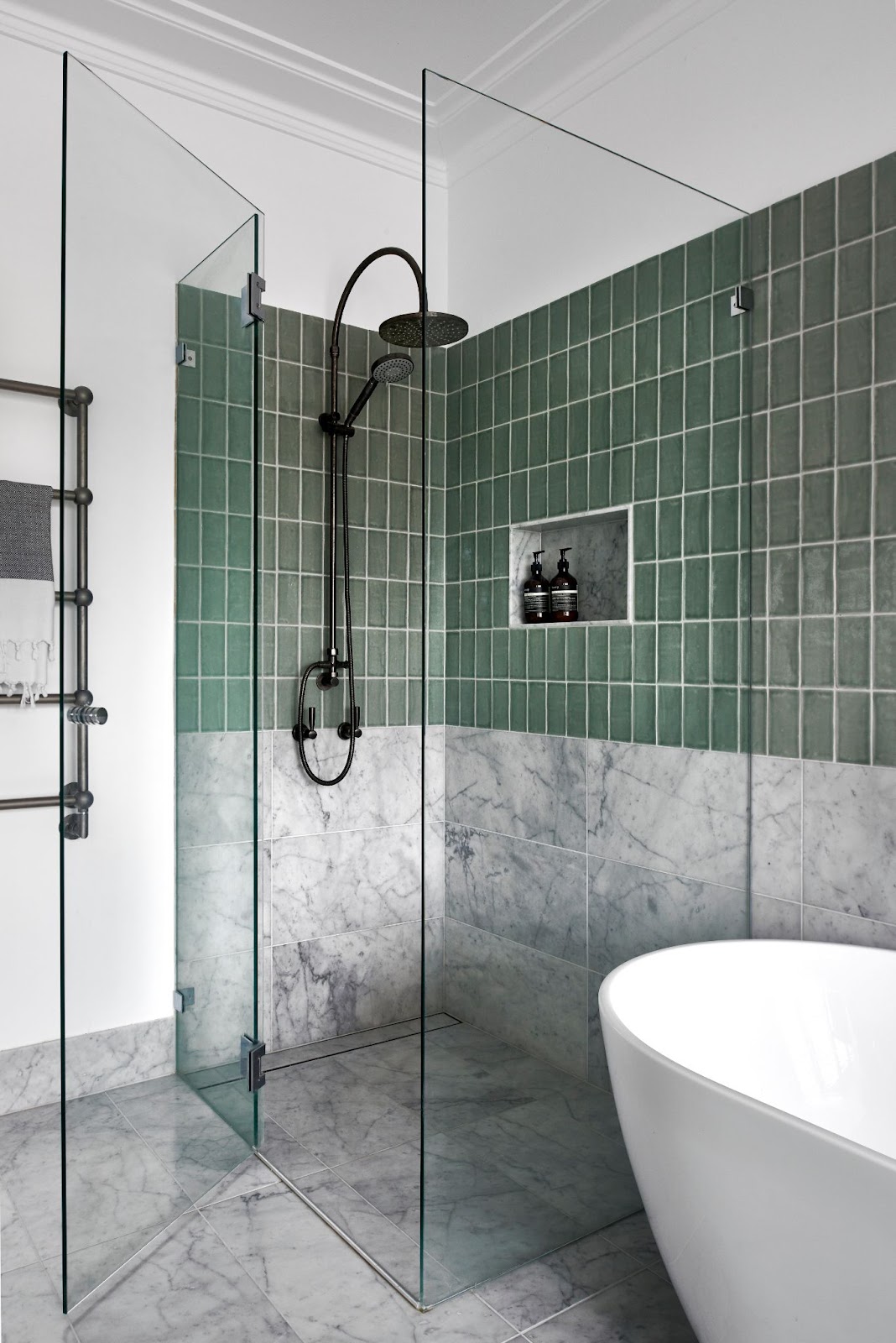 Frameless shower screen with hinge panel, door and return panel in polished chrome hardware, sage green tiles and marble floor